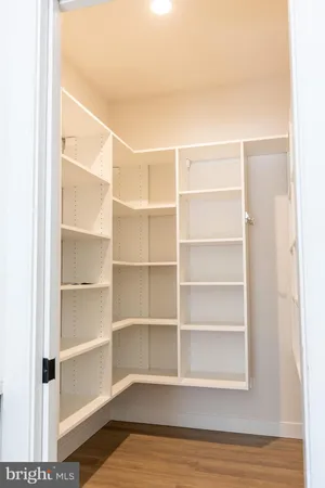 a view of a kitchen with wooden floor and white cabinets
