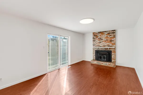 an empty room with wooden floor fireplace and windows