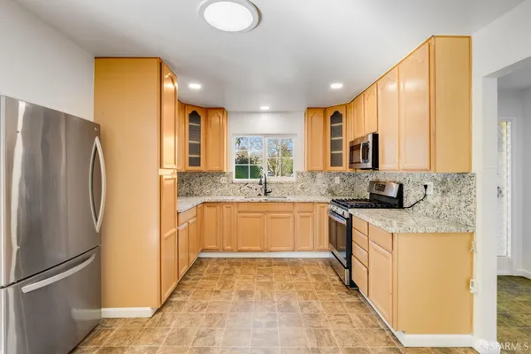a large kitchen with stainless steel appliances granite countertop a refrigerator and a stove top oven