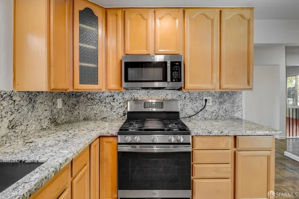 a kitchen with granite countertop a stove top oven microwave and cabinets