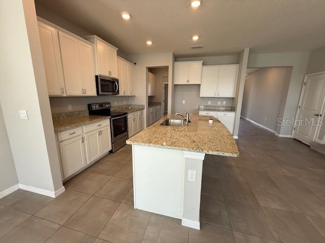 5644 Flagstone Trail Palmetto, FL 34221 - Photo 4 of 25 a kitchen with kitchen island granite countertop a sink a counter top space stainless steel appliances and cabinets