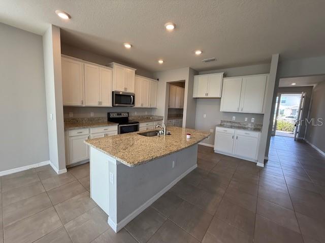 5644 Flagstone Trail Palmetto, FL 34221 - Photo 5 of 25 a kitchen with stainless steel appliances granite countertop a stove top oven a refrigerator a sink and a microwave
