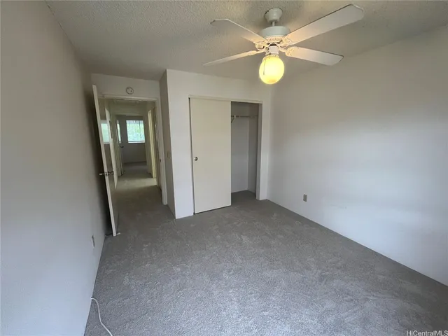 an empty room with closet and a chandelier fan