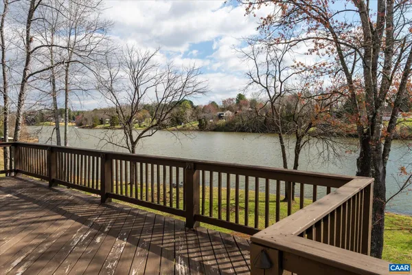 an aerial view of a house with a yard lake and trees all around