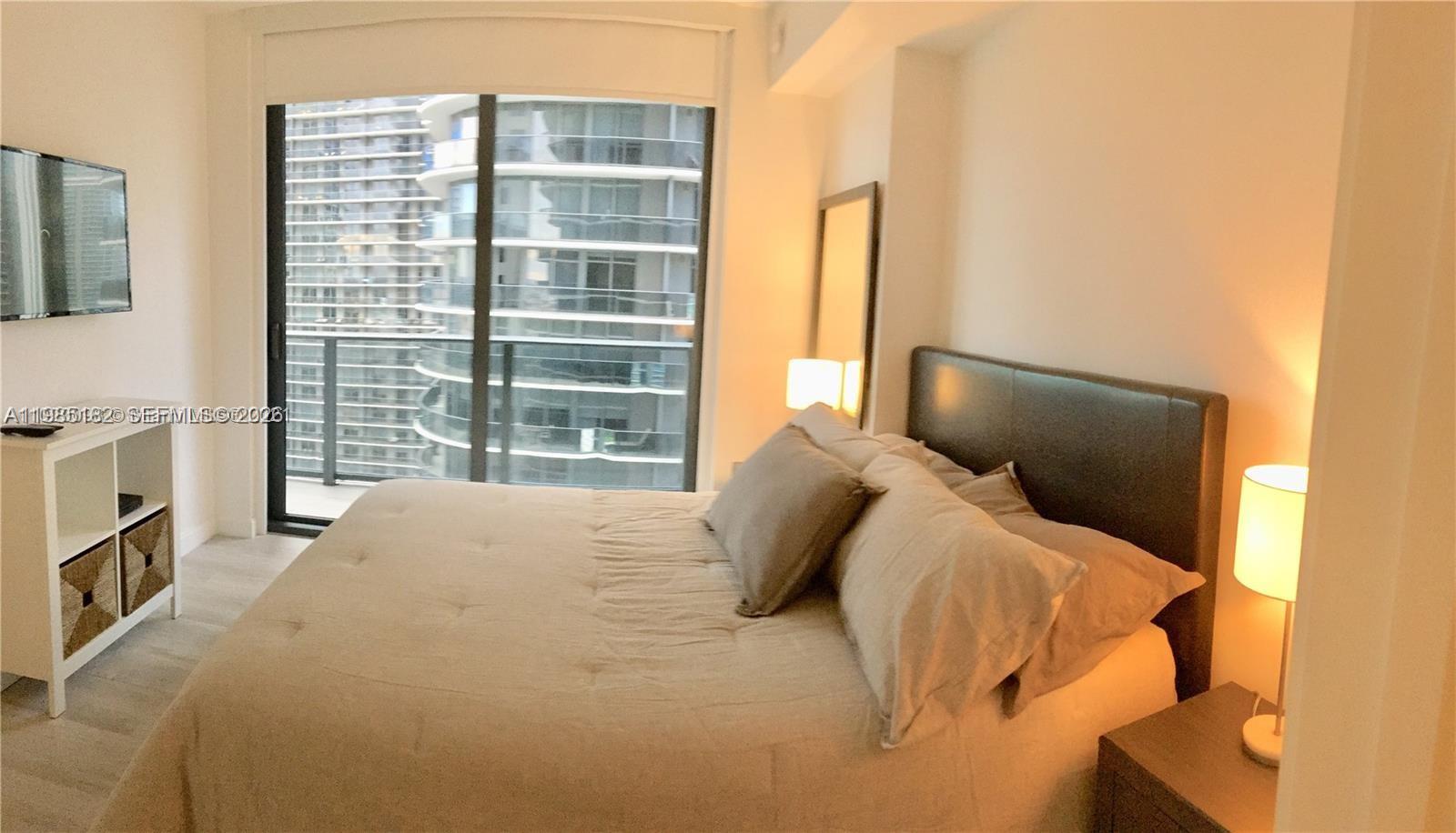 55 Southwest 9th Street, Unit 2901 Miami, FL 33130 - Photo 11 of 20 a bedroom with a bed and a flat tv screen next to a window