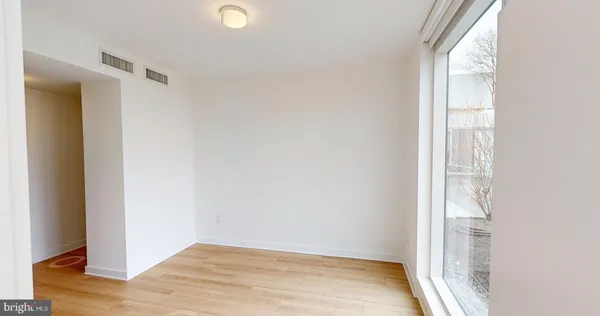 a view of an empty room with wooden floor and a window