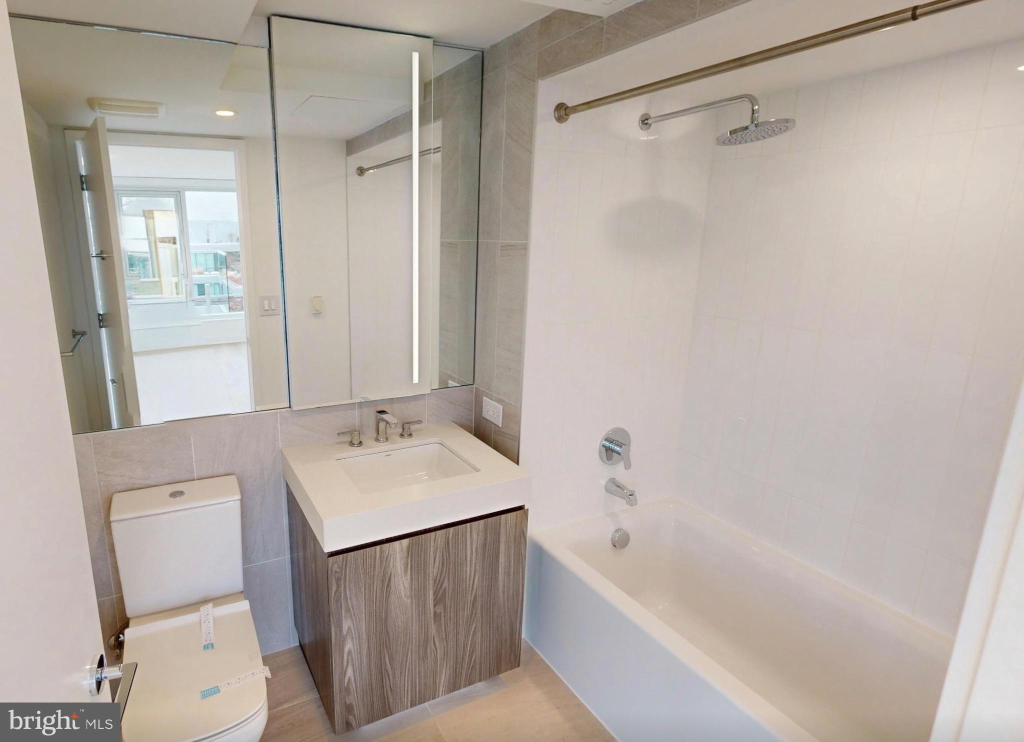 1201 Half Street Southwest, Unit PH1201 Washington, DC 20003 - Photo 16 of 26 a bathroom with a sink a toilet a mirror and a bathtub