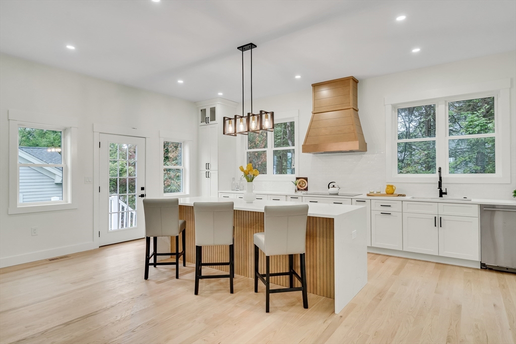 22 Estabrook Road Lexington, MA 02421 - Photo 11 of 35 a kitchen with white cabinets a sink dining table and chairs