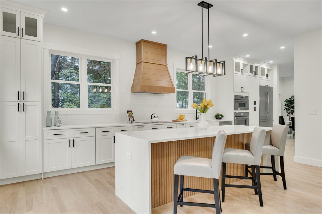 22 Estabrook Road Lexington, MA 02421 - Photo 12 of 35 a kitchen with stainless steel appliances kitchen island a table chairs in it and wooden floors