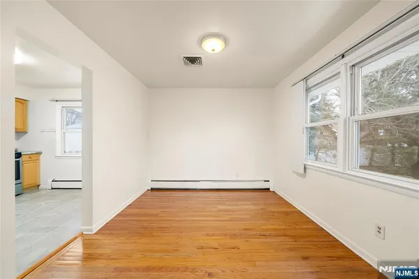 a view of empty room with wooden floor and fan