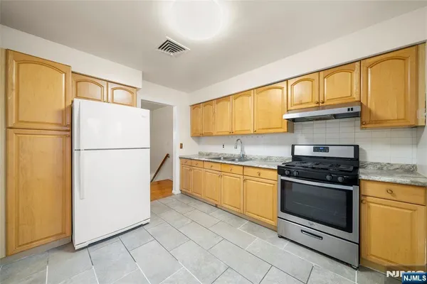 a kitchen with granite countertop a refrigerator stove top oven and sink