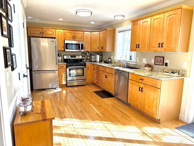 a kitchen with granite countertop a refrigerator a sink a stove top oven and cabinetry