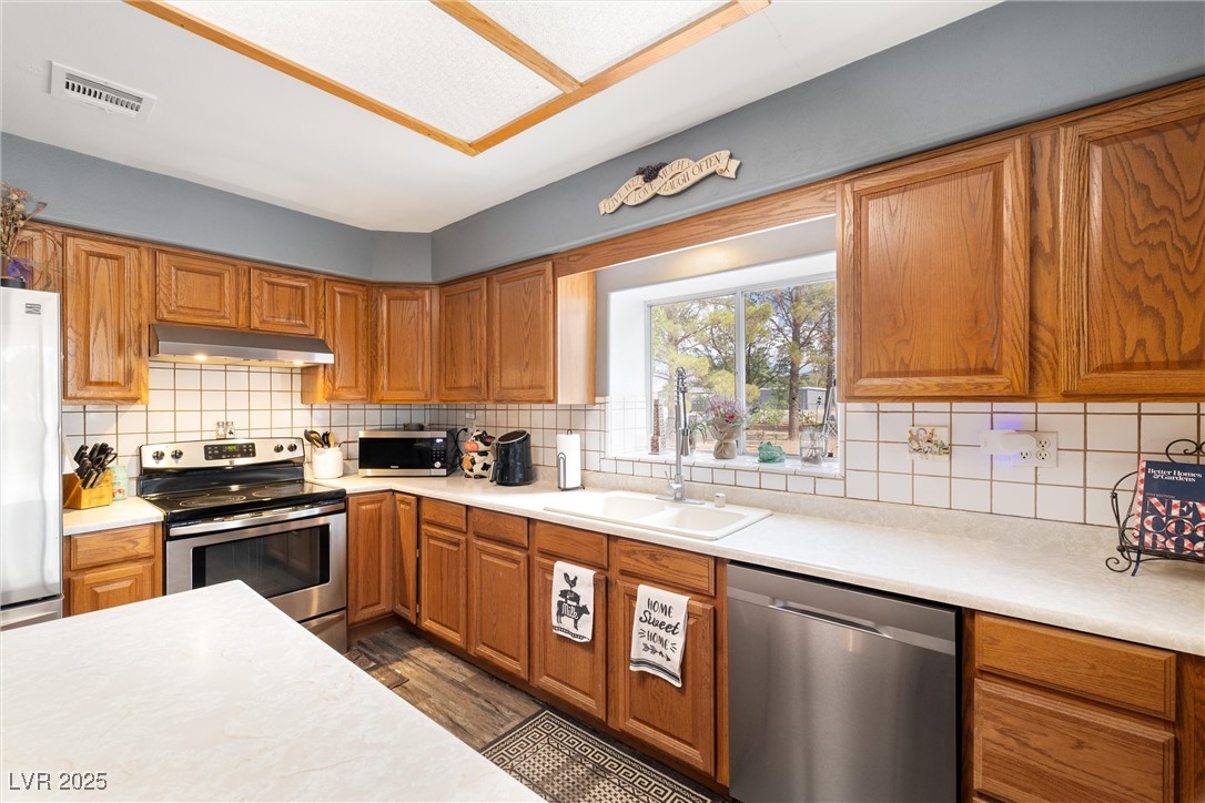3951 West Blosser Ranch Road Pahrump, NV 89060 - Photo 13 of 35 Kitchen featuring appliances with stainless steel finishes, under cabinet range hood, and light countertops