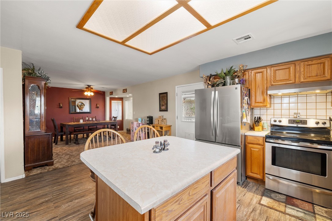 3951 West Blosser Ranch Road Pahrump, NV 89060 - Photo 14 of 35 Kitchen featuring appliances with stainless steel finishes, under cabinet range hood, light countertops, light wood-style floors, and tasteful backsplash