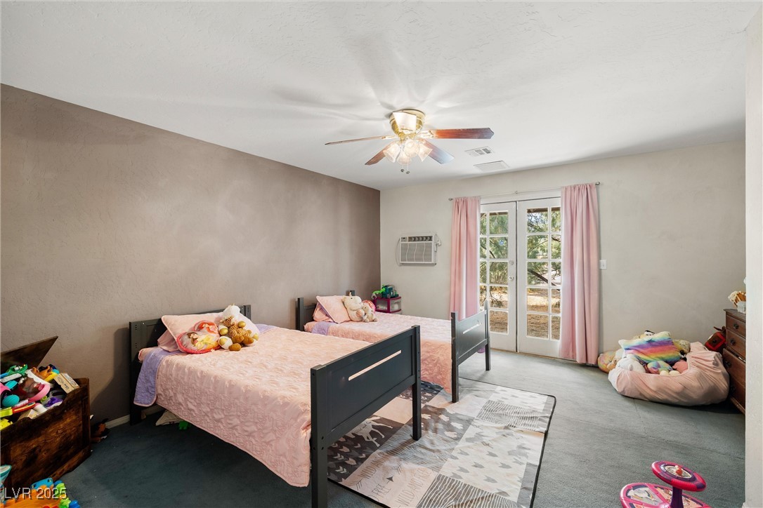 3951 West Blosser Ranch Road Pahrump, NV 89060 - Photo 18 of 35 Bedroom featuring light carpet, access to outside, a wall mounted AC, and ceiling fan