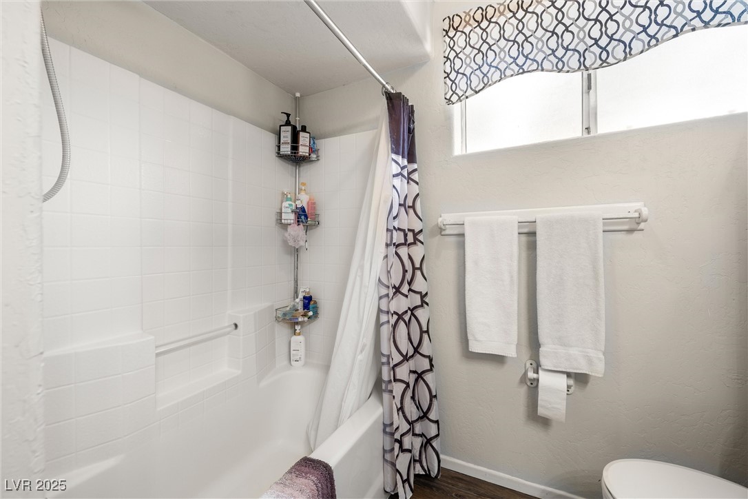 3951 West Blosser Ranch Road Pahrump, NV 89060 - Photo 23 of 35 Bathroom featuring shower / bathtub combination with curtain and wood finished floors