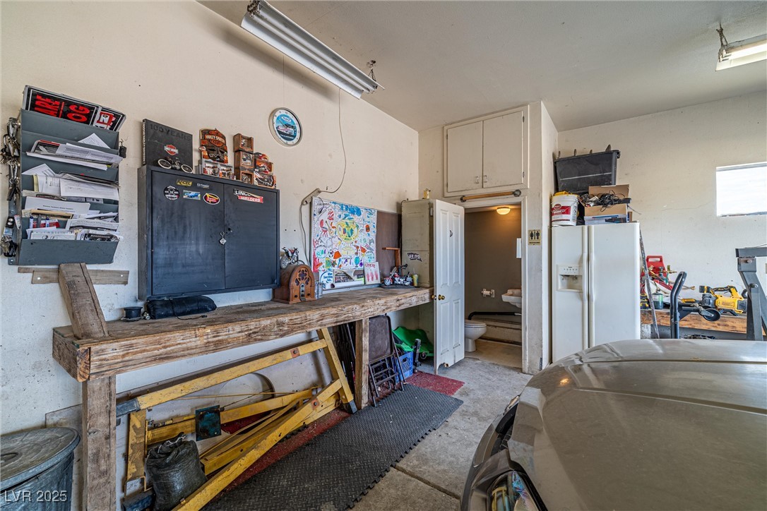 3951 West Blosser Ranch Road Pahrump, NV 89060 - Photo 29 of 35 Garage featuring white refrigerator with ice dispenser and a workshop area