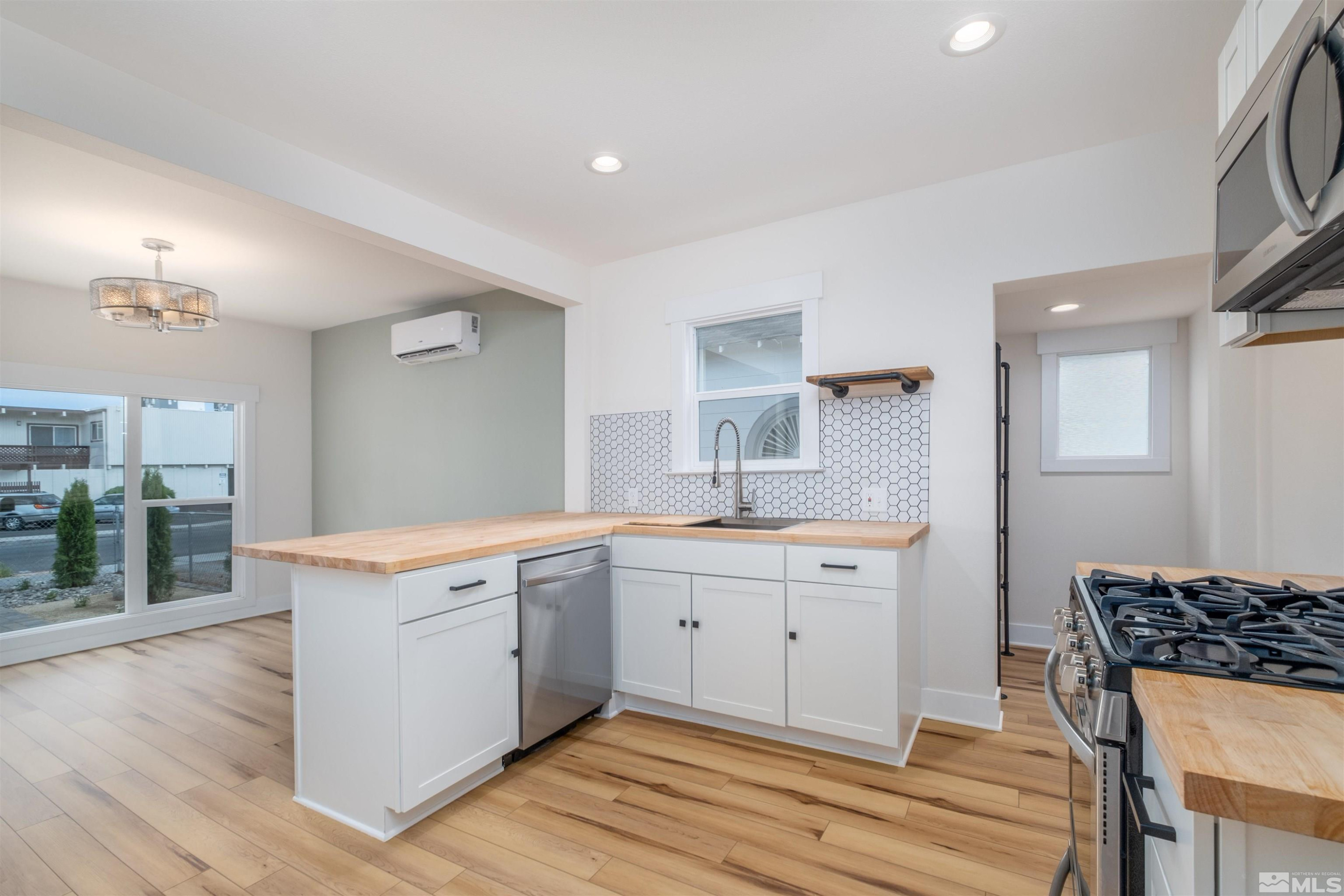 1401 Locust Street Reno, NV 89502 - Photo 17 of 29 a large kitchen with a stove a sink dishwasher and a dining table with wooden floor