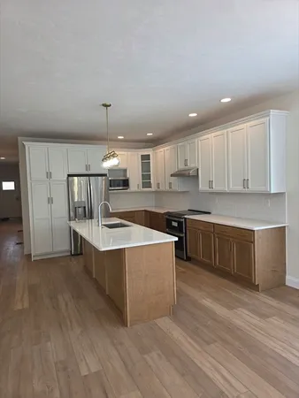 a view of kitchen with stainless steel appliances granite countertop a stove a sink dishwasher and a refrigerator with wooden floor