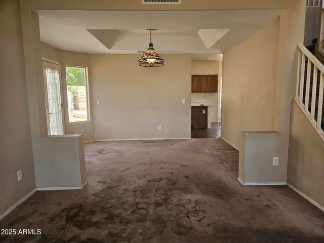 an empty room with windows and chandelier fan