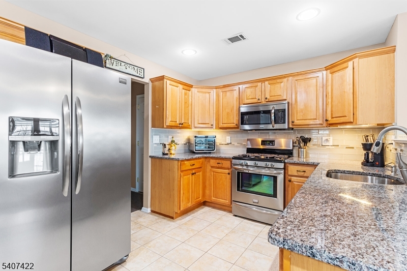 124 Ridge Drive Pompton Lakes, NJ 07442 - Photo 10 of 32 a kitchen with stainless steel appliances granite countertop a refrigerator a stove top oven a sink and dishwasher