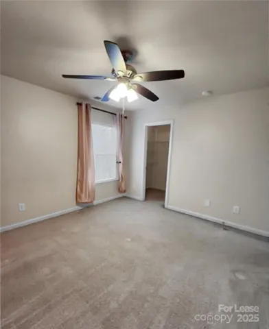 a view of an empty room and chandelier fan