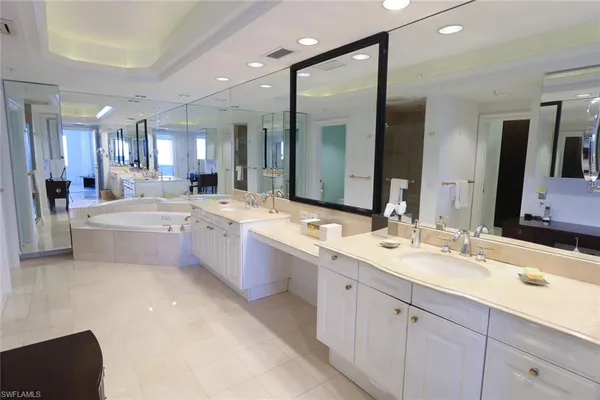a large white bathroom with a double vanity sink a mirror and a bathtub