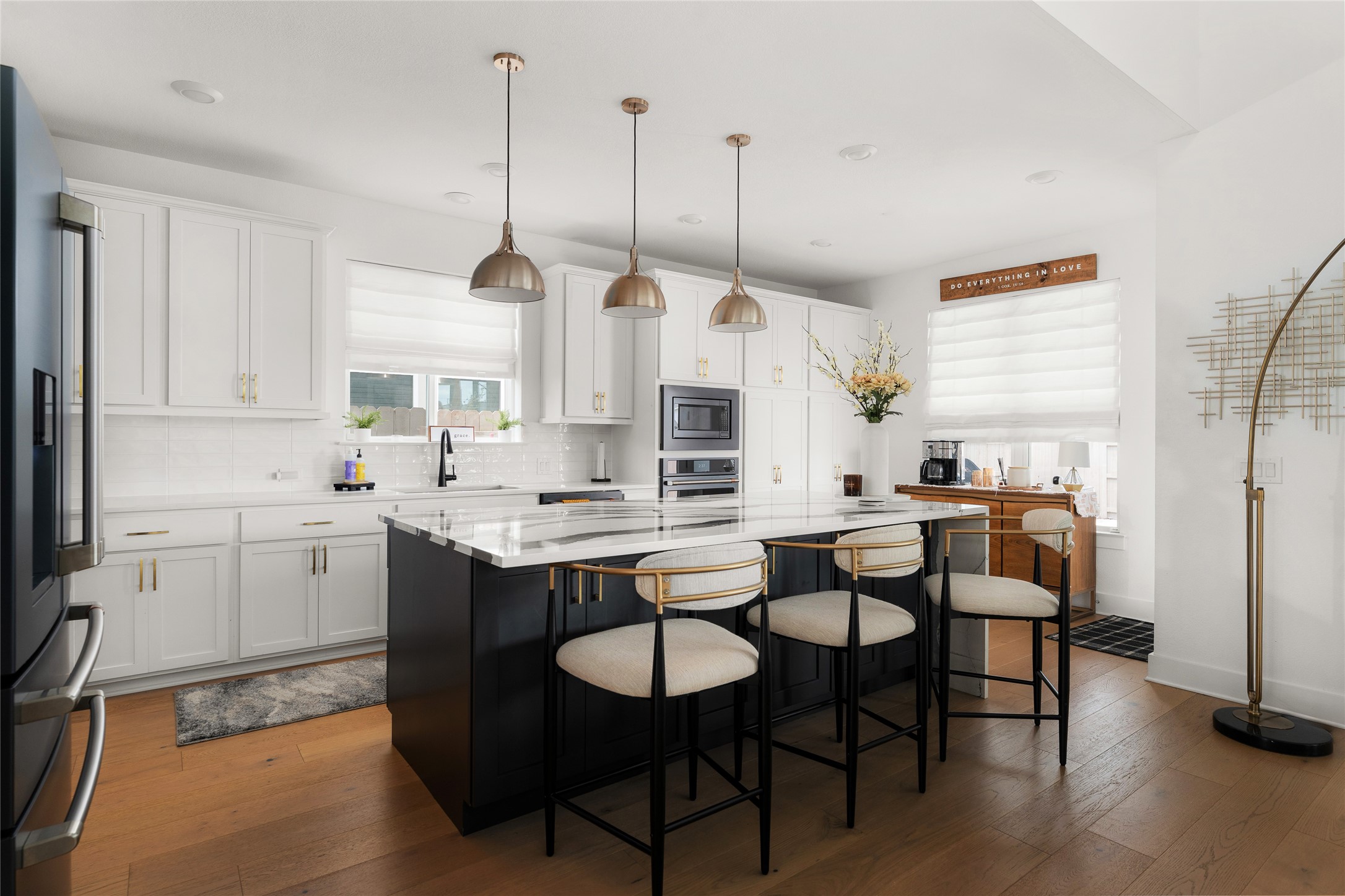 7917 Edmondson Bend Austin, TX 78744 - Photo 8 of 24 Kitchen featuring a large central island with seating, white shaker cabinetry, stainless steel appliances, wood-finish flooring, and pendant lighting