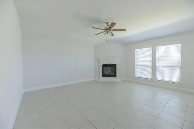 an empty room with windows and fireplace