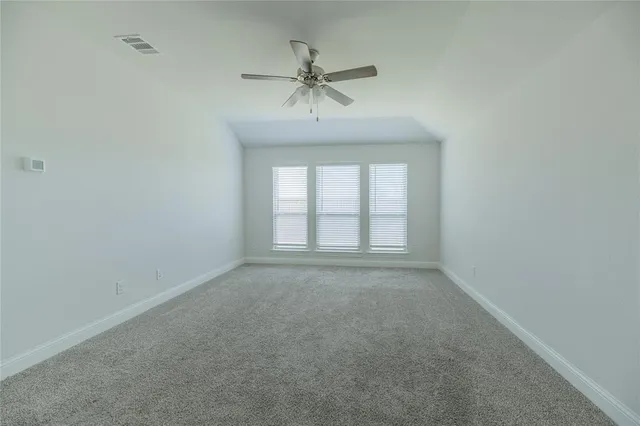 an empty room with a ceiling fan and window
