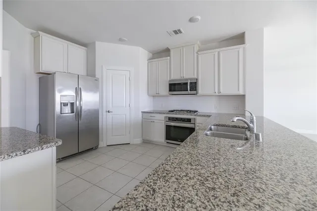 a kitchen with kitchen island granite countertop a stove a refrigerator and a sink