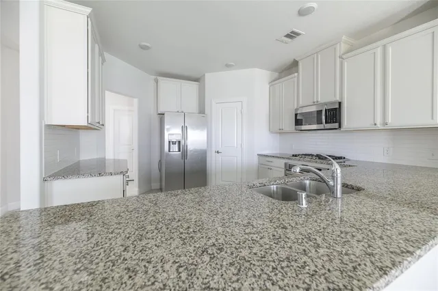 a kitchen with stainless steel appliances granite countertop a refrigerator and a stove top oven