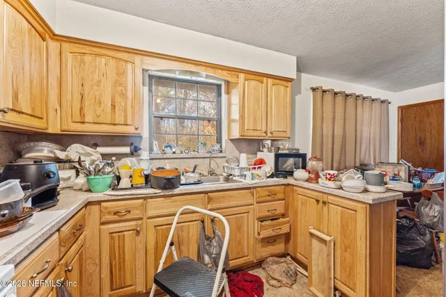 a kitchen with stainless steel appliances a sink a stove a refrigerator cabinets and a window