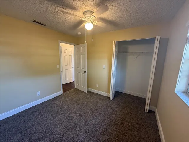 an empty room with closet and a ceiling fan