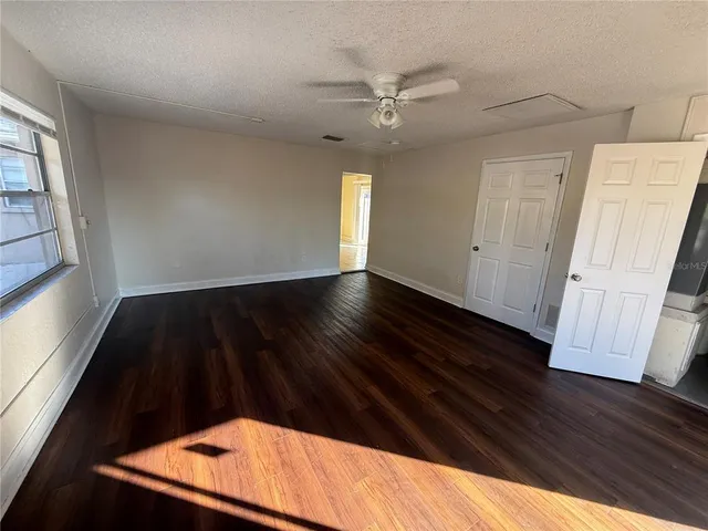 an empty room with wooden floor fan and window