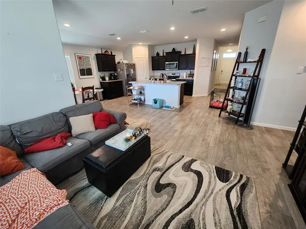 a living room with furniture kitchen and a wooden floor