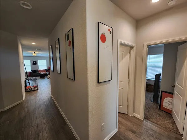 a view of a hallway with stainless steel appliances a refrigerator and a view of living room