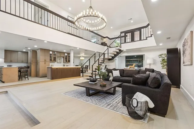 a living room with furniture kitchen view and a chandelier