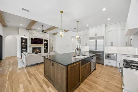 a kitchen with stainless steel appliances kitchen island a large counter top space a sink a stove and a wooden floors