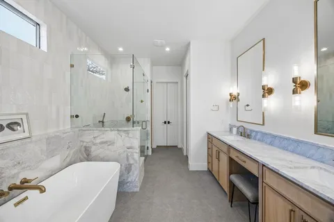 a spacious bathroom with a granite countertop tub sink double and mirror