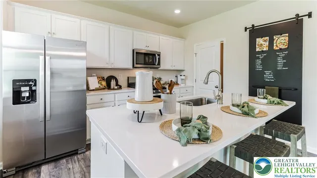 a kitchen with stainless steel appliances a refrigerator a sink a stove a table and chairs