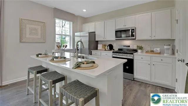 a kitchen with stainless steel appliances kitchen island granite countertop a sink a stove a table and chairs