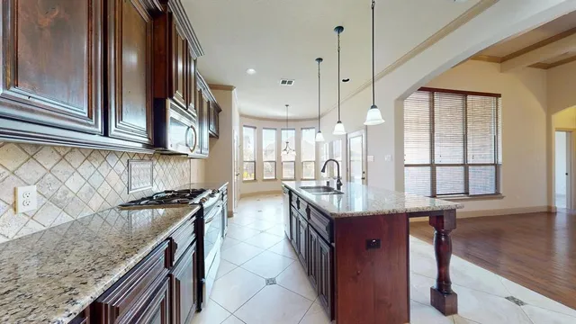 a kitchen with a stove a sink a center island and wooden cabinets