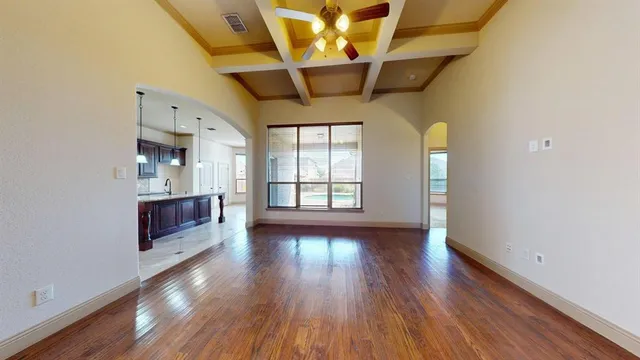 a view of an empty room with kitchen and fireplace
