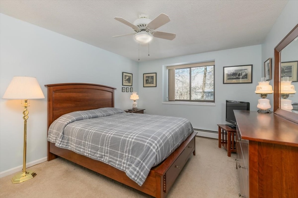 42 Main Street, Unit 22 North Reading, MA 01864 - Photo 20 of 37 a bedroom with a bed a table and chair with a mirror