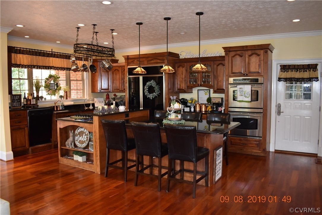 872 Wilson Road Wilsons, VA 23894 - Photo 6 of 34 a kitchen with stainless steel appliances granite countertop a refrigerator a stove top oven a dining table and chairs with wooden floor