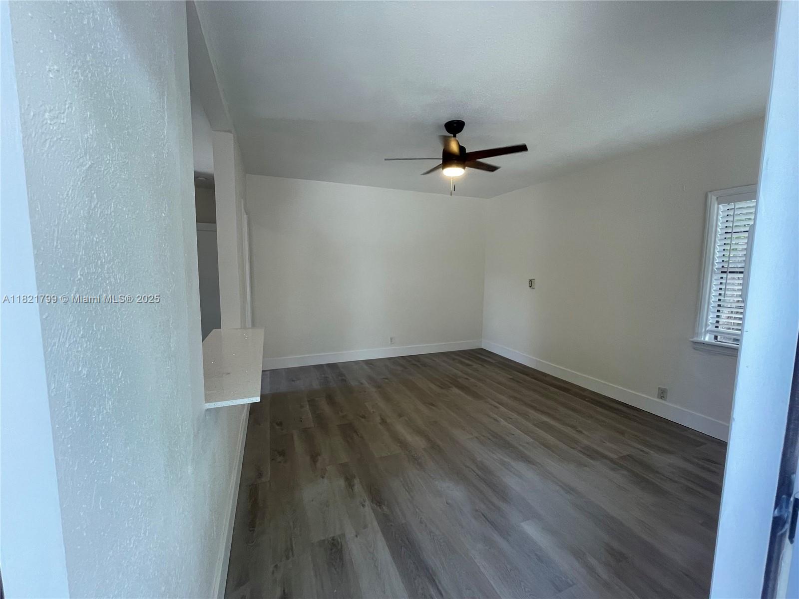 126 Northeast 19th Avenue, Unit 1 Pompano Beach, FL 33060 - Photo 2 of 7 a view of a room with wooden floor and fan