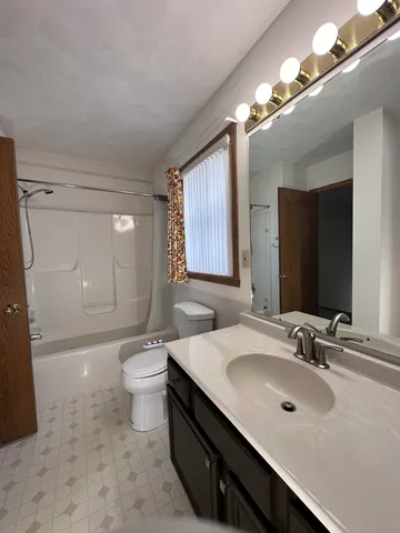 a spacious bathroom with a bathtub sink mirror and toilet