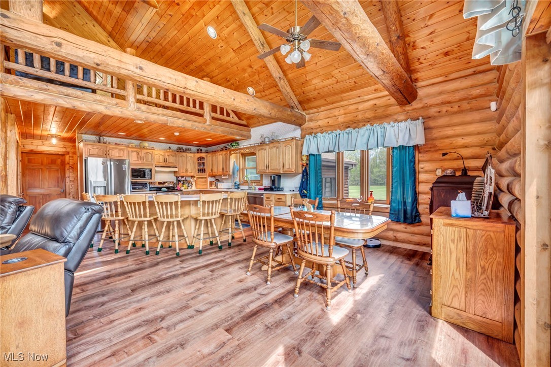 15180 Stoltz Road Diamond, OH 44412 - Photo 13 of 48 Dining area featuring wooden ceiling, ceiling fan, light wood finished floors, beam ceiling, and log walls