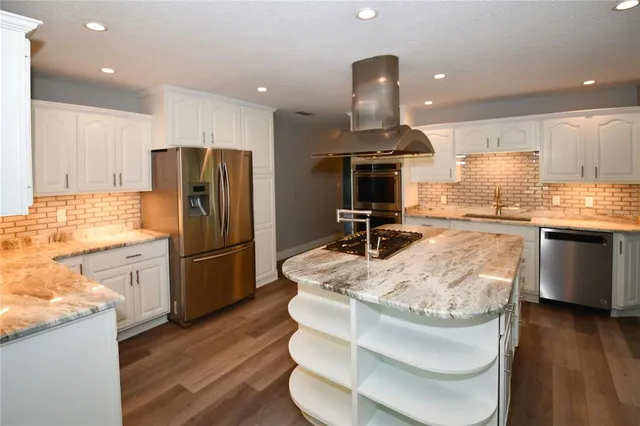 a kitchen with kitchen island stainless steel appliances a sink and a refrigerator